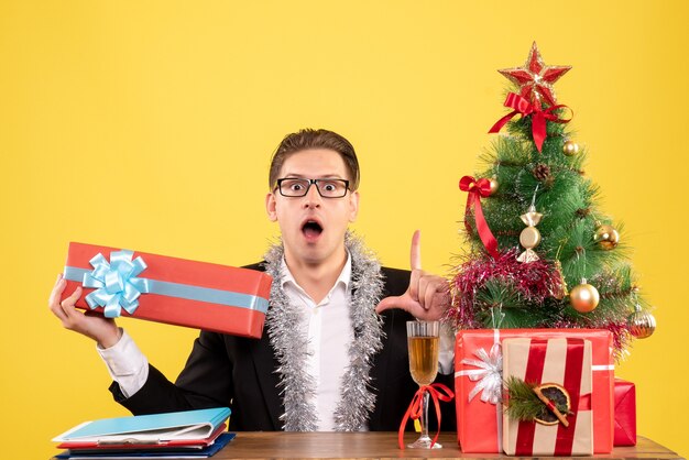 Vista frontal trabajador masculino sentado y celebrando la Navidad