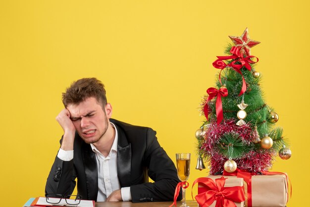 Vista frontal del trabajador masculino sentado detrás de su lugar de trabajo en amarillo