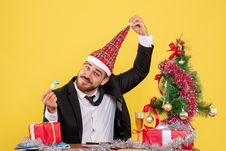 Foto gratuito vista frontal trabajador masculino sentado detrás de su mesa con regalos en amarillo