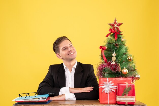 Vista frontal del trabajador masculino sentado detrás de su mesa de trabajo con una sonrisa