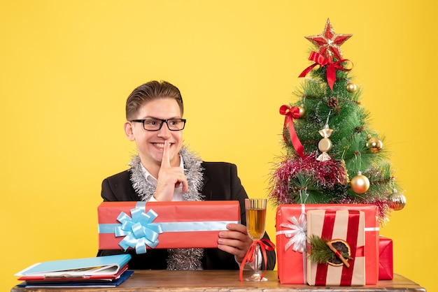 Vista frontal trabajador masculino sentado y sosteniendo el regalo de Navidad