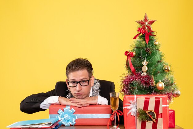 Vista frontal trabajador masculino sentado y sosteniendo el regalo de Navidad