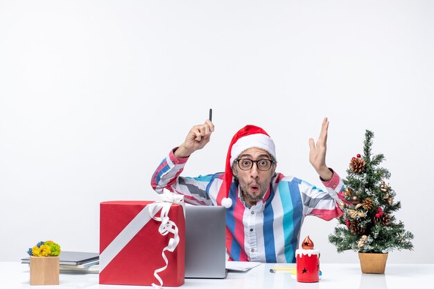 Vista frontal del trabajador masculino sentado en su lugar escribiendo notas y usando laptop emoción oficina trabajo de navidad