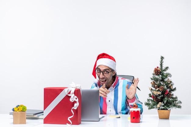 Vista frontal trabajador masculino sentado en su lugar con laptop y archivos emocionado trabajo de oficina emoción de navidad