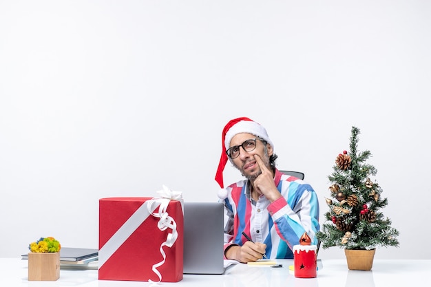 Vista frontal trabajador masculino sentado en su lugar con laptop y archivos escribiendo notas trabajo de oficina de vacaciones de navidad