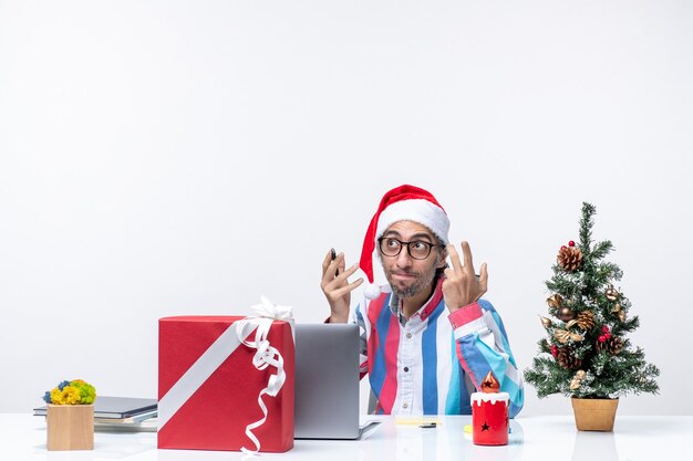 Vista frontal trabajador masculino sentado en su lugar con laptop y archivos posando oficina emoción trabajo navidad