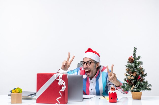 Vista frontal trabajador masculino sentado en su lugar posando emoción oficina trabajo de navidad