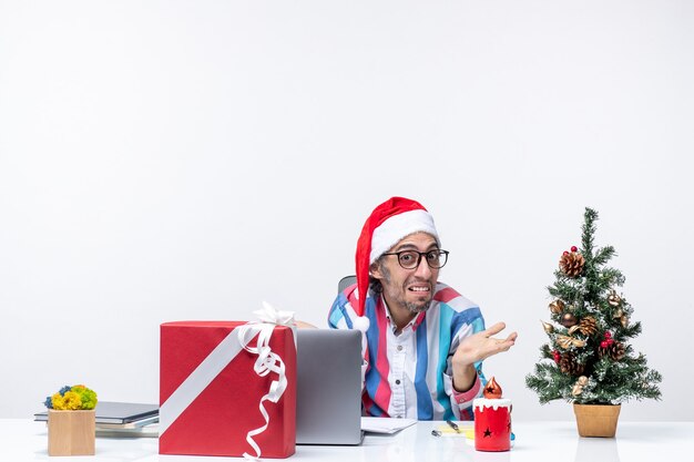 Vista frontal trabajador masculino sentado en su lugar de trabajo emoción oficina trabajo de navidad