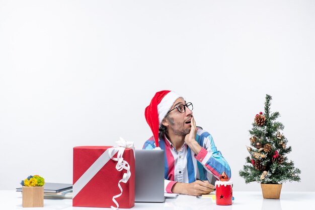 Vista frontal del trabajador masculino sentado en su lugar de trabajo escribiendo notas