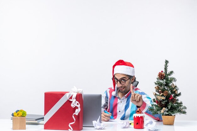 Vista frontal del trabajador masculino sentado en su lugar de trabajo escribiendo notas