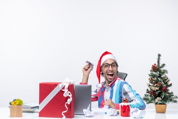 Vista frontal del trabajador masculino sentado en su lugar de trabajo jugando con el avión de papel, trabajo comercial, oficina de navidad