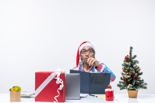 Vista frontal trabajador masculino sentado en su lugar de trabajo leyendo copybook oficina trabajo de negocios de navidad emoción