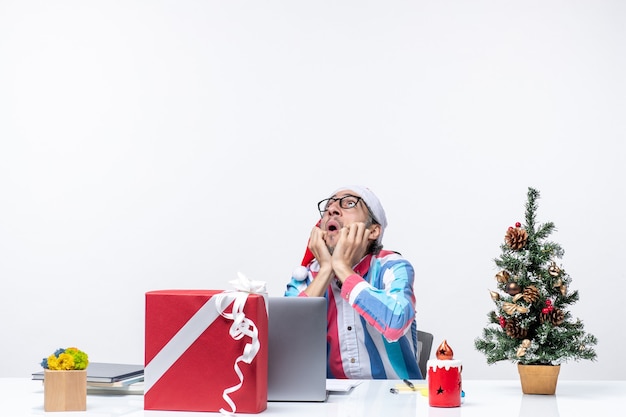 Vista frontal del trabajador masculino sentado en su lugar de trabajo mirando el trabajo de emoción navideña de negocios de techo