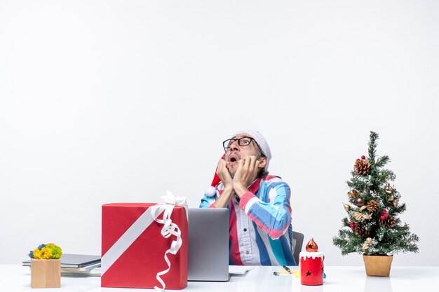 Vista frontal del trabajador masculino sentado en su lugar de trabajo mirando el trabajo de emoción navideña de negocios de techo