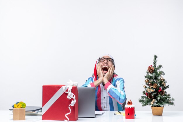 Vista frontal trabajador masculino sentado en su lugar de trabajo negocios trabajo de navidad emociones