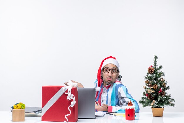 Vista frontal trabajador masculino sentado en su lugar de trabajo oficina emoción trabajo navidad trabajo empresarial