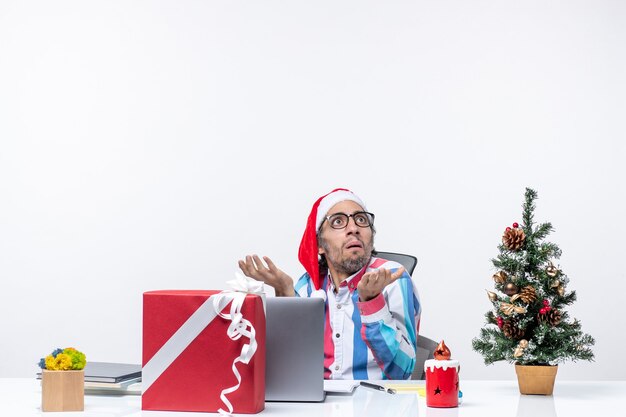 Vista frontal trabajador masculino sentado en su lugar de trabajo oficina emoción trabajo negocio de navidad