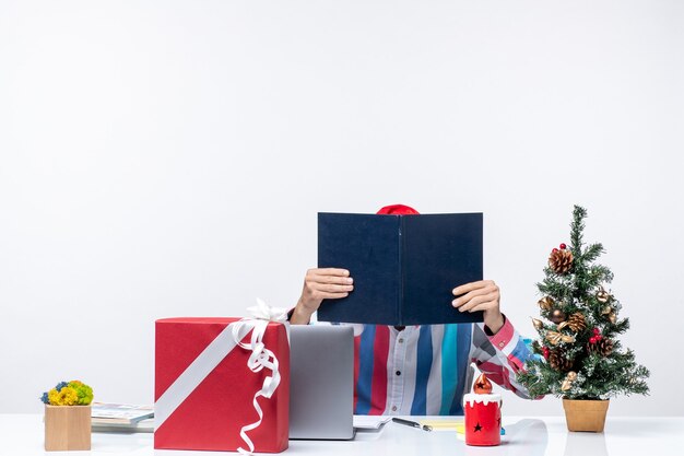 Vista frontal del trabajador masculino sentado en su lugar de trabajo sosteniendo la oficina de navidad de emociones de trabajo de negocios de cuaderno