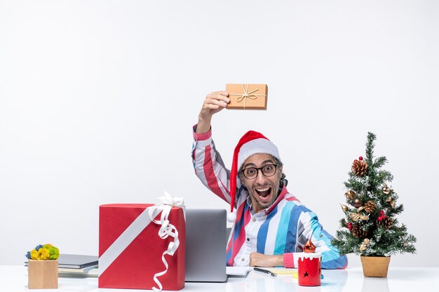 Vista frontal del trabajador masculino sentado en su lugar de trabajo sosteniendo el paquete