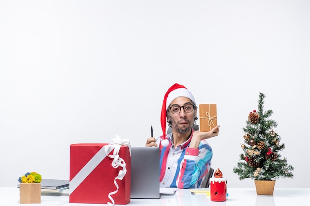 Vista frontal del trabajador masculino sentado en su lugar de trabajo sosteniendo el paquete