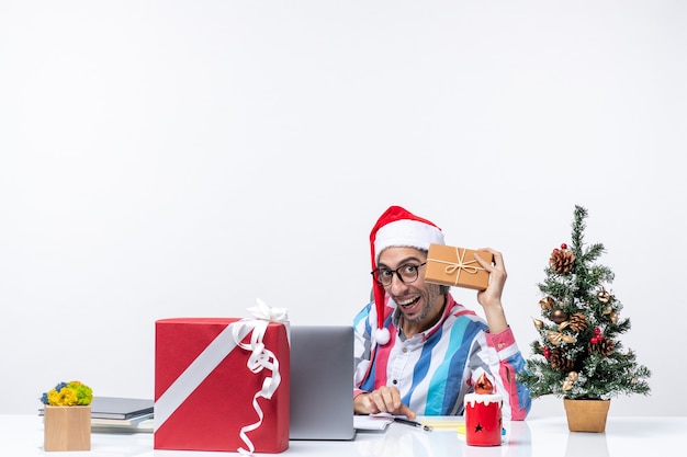 Vista frontal del trabajador masculino sentado en su lugar de trabajo sosteniendo el paquete