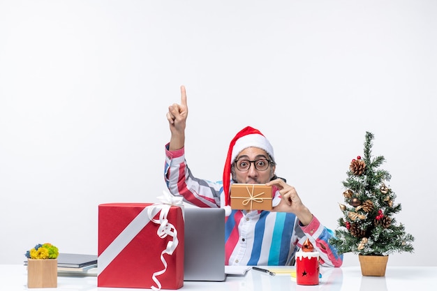 Vista frontal del trabajador masculino sentado en su lugar de trabajo sosteniendo el paquete