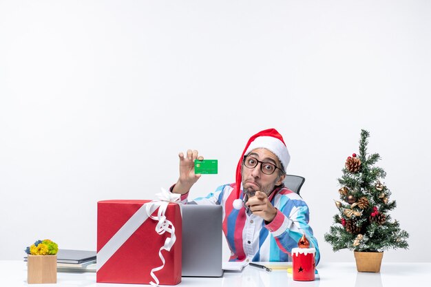 Vista frontal del trabajador masculino sentado en su lugar de trabajo con tarjeta bancaria verde