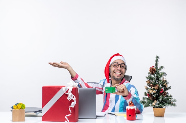 Vista frontal del trabajador masculino sentado en su lugar de trabajo con tarjeta bancaria verde