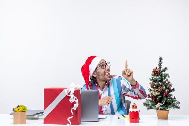 Vista frontal trabajador masculino sentado en su lugar de trabajo trabajo de emociones de navidad de negocios