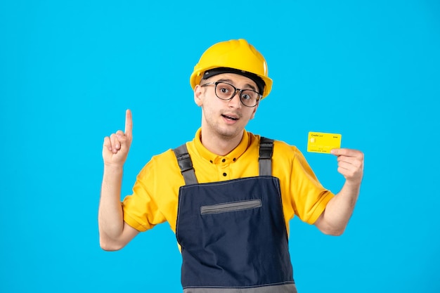 Vista frontal del trabajador masculino en uniforme amarillo con tarjeta de crédito en azul