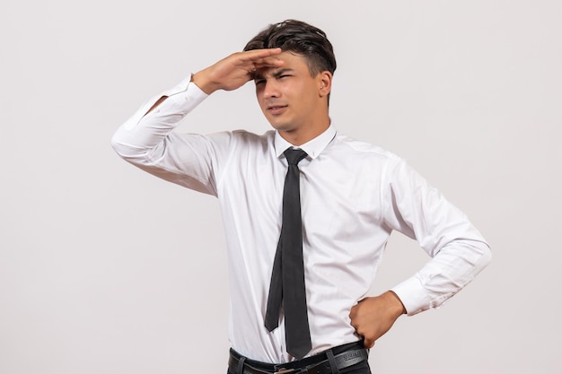 Vista frontal trabajador de oficina masculino mirando a distancia en la pared blanca trabajo de negocios trabajo masculino