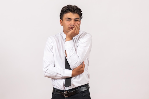 Vista frontal del trabajador de oficina masculino que se siente aburrido en la pared blanca trabajo trabajo masculino negocio