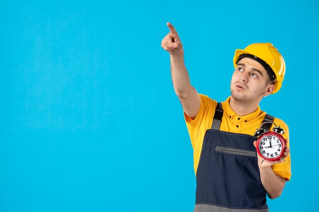 Vista frontal del trabajador de sexo masculino en uniforme amarillo con relojes apuntando en azul