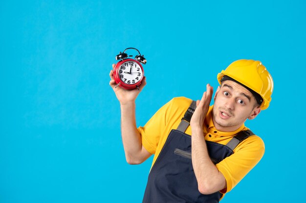 Vista frontal del trabajador de sexo masculino en uniforme asustado de los relojes en azul