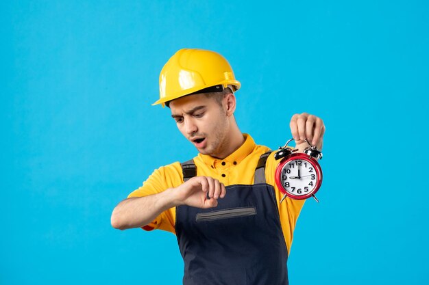 Vista frontal del trabajador de sexo masculino en uniforme con relojes en azul