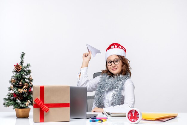 Vista frontal trabajadora sentada antes de su lugar de trabajo jugando con aviones de papel trabajo emoción oficina de trabajo de negocios navidad