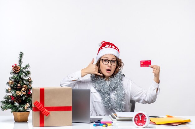 Vista frontal trabajadora sentada antes de su lugar de trabajo con tarjeta bancaria dinero trabajo trabajo comercial oficina de navidad