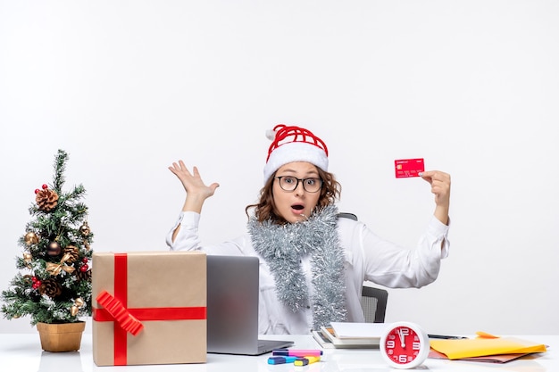 Vista frontal trabajadora sentada antes de su lugar de trabajo con tarjeta bancaria trabajo trabajo de negocios oficina dinero de navidad