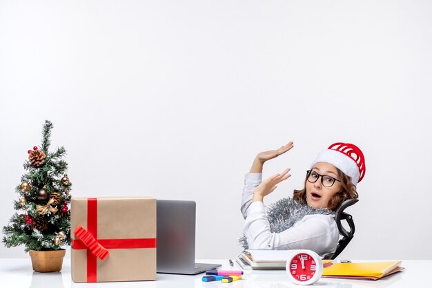 Vista frontal trabajadora sentada antes de su lugar de trabajo trabajo de oficina trabajo negocio navidad