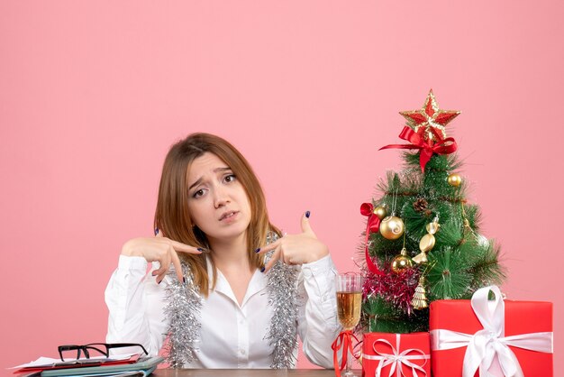 Vista frontal de la trabajadora sentada detrás de su mesa en rosa