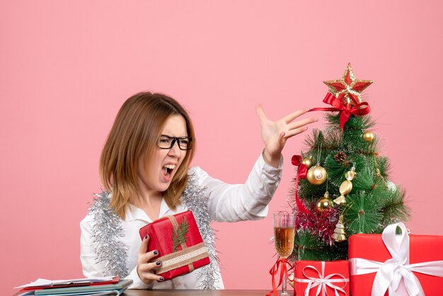 Vista frontal de la trabajadora sentada con regalos de Navidad en rosa