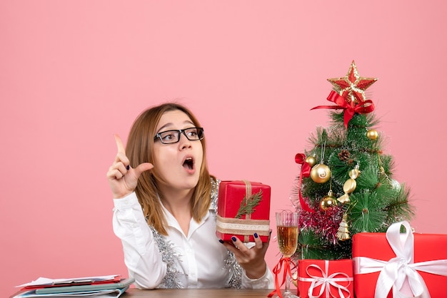 Vista frontal de la trabajadora sentada con regalos de Navidad en rosa