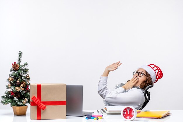 Vista frontal trabajadora sentada ante su lugar de trabajo conmocionado trabajo oficina trabajo negocio navidad