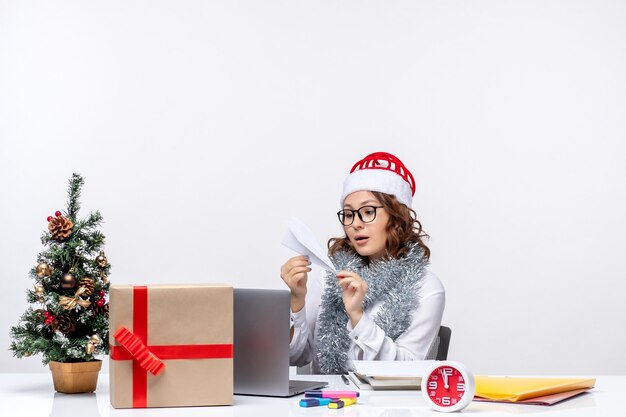 Vista frontal trabajadora sentada ante su lugar de trabajo haciendo aviones de papel trabajo trabajo emoción oficina de negocios navidad