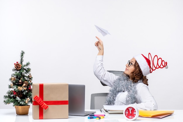 Vista frontal trabajadora sentada ante su lugar de trabajo jugando con aviones de papel trabajo trabajo emoción negocio navidad