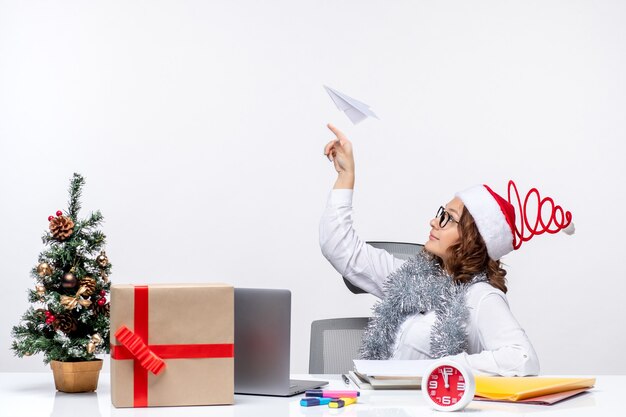 Vista frontal trabajadora sentada ante su lugar de trabajo jugando con aviones de papel trabajo trabajo emoción negocio navidad
