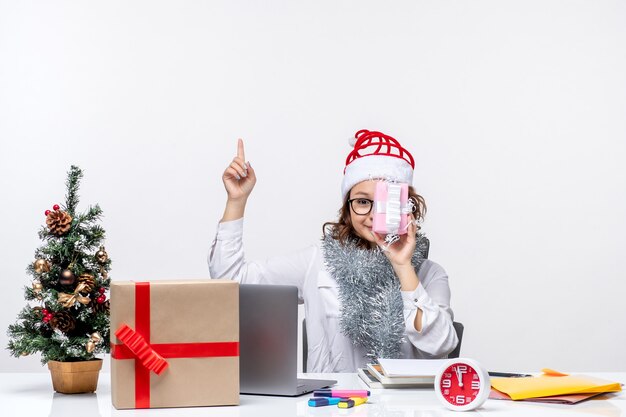 Vista frontal trabajadora sentada ante su lugar de trabajo sosteniendo poco trabajo de mujer presente trabajo de oficina de Navidad negocio