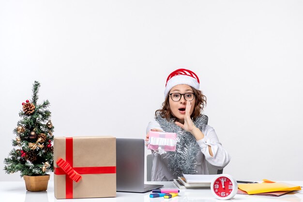 Vista frontal trabajadora sentada ante su lugar de trabajo sosteniendo poco trabajo de mujer presente trabajo trabajo de navidad