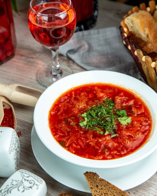 Vista frontal tradicional borscht ucraniano con rebanadas de pan integral y un refresco