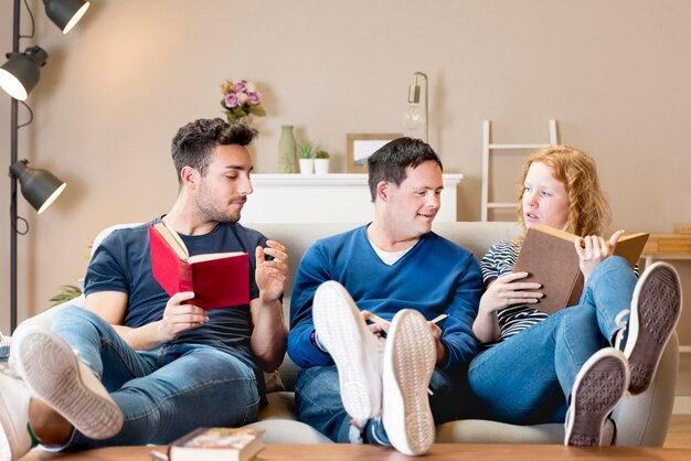 Vista frontal de tres amigos en el sofá con libros